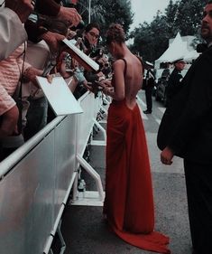 a woman in a red dress signing autographs for fans