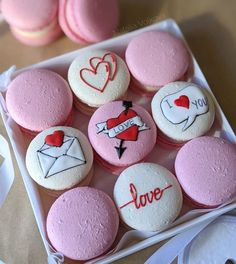 pink and white cupcakes with love written on them in a square box next to some cookies