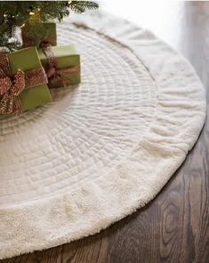 a small christmas tree with presents under it on a round rug in the living room