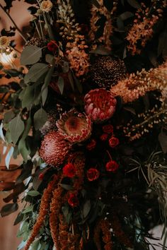 an arrangement of flowers and greenery is displayed