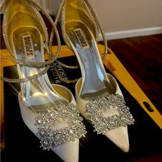 white high heels with crystal embellishments are on display in front of a mirror