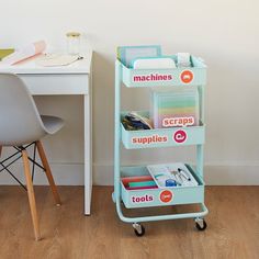 there is a blue cart with lots of supplies on it next to a white desk