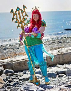 a woman dressed as merida from the little mermaid holding a gold and blue staff