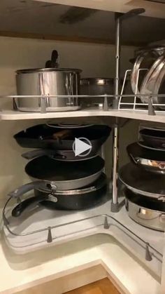 pots and pans are sitting on shelves in the corner of a kitchen cabinet,