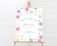 a welcome sign is on an easel with hearts in pastel colors and the words, welcome to always baby shower