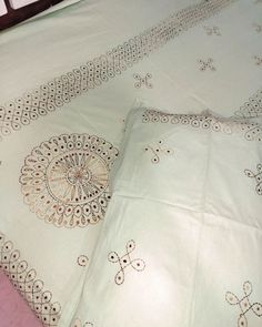 two white bedspreads with embroidered designs on them