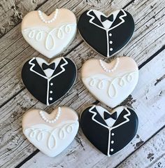 four decorated cookies in the shape of hearts with tuxedos and pearls on them