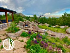 an outdoor area with rocks and flowers in the foreground, along with a gazebo