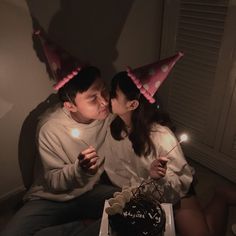 two people sitting next to each other in front of a cake with candles on it