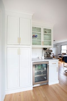 a kitchen with white cabinets and wood floors