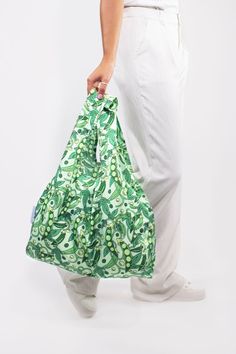 a person is holding a green bag in their left hand and white pants on the other side