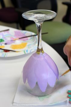 a person is painting a glass vase on a table