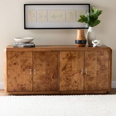 a wooden cabinet with two vases on top of it next to a white rug