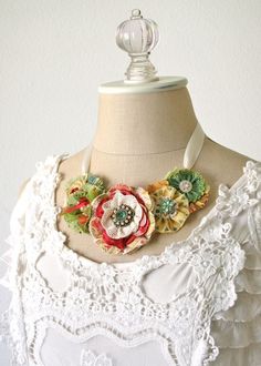 a mannequin wearing a white dress with flowers on the neck and an attached necklace