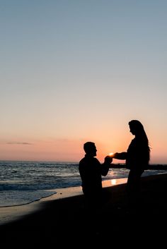 two people are standing on the beach and one person is holding something in his hand