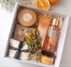 an open box containing oranges, body lotion and other items next to some flowers