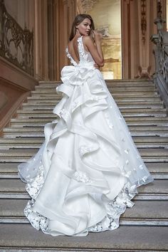 a woman in a wedding dress standing on some stairs with her hands behind her back