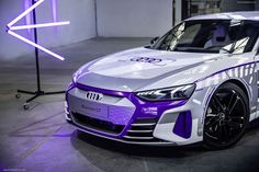 an electric car is displayed in a showroom with purple lighting on the wall and floor