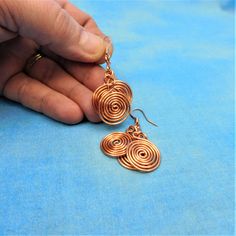 Non tarnish bright copper wire is hand sculpted into three spiral swirls, creating a cascade of circles. These dangle earrings are lightweight, comfortable, and fun to wear. The swirls are 3/4 inch each, and the total length of each earring is 1 1/2 inches from the bottom of the ear wire to the bottom of the last circle. Your unique earrings are ready to ship via USPS to your US location at no extra cost. (International shipping available. Please be aware of your local laws related to customs an Wire Wrapped Spiral Copper Earrings, Copper Spiral Wire Wrapped Earrings, Wire Wrapped Copper Spiral Earrings, Spiral Copper Wire Jewelry With Ear Wire, Bronze Spiral Earrings For Gifts, Bohemian Spiral Copper Earrings, Bohemian Copper Spiral Earrings, Nickel-free Spiral Copper Jewelry, Spiral Copper Wire Earrings As Gift