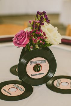 three records are sitting on top of a table with flowers in the center and one is black