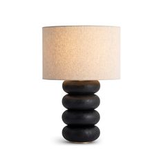 a lamp that is sitting on top of a wooden base with a white shade over it