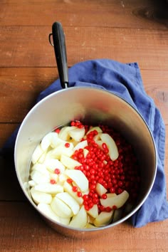 apples and pomegranates in a pot on a wooden table with a blue towel