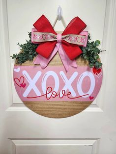 a wooden sign that says xoxo love hanging on the front door with a bow