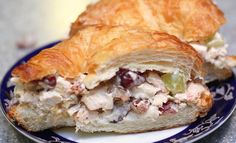 a croissant filled with chicken salad on top of a blue and white plate