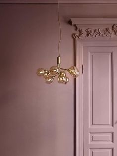 a room with pink walls and a gold chandelier hanging from it's ceiling