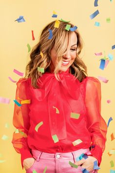 a woman standing in front of confetti on a yellow background