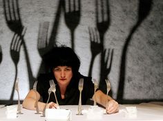 a woman sitting at a table with forks and spoons in front of her shadow