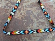 a multicolored beaded lanyard on a stone surface with a black cord