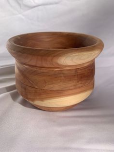 a wooden bowl sitting on top of a white sheet