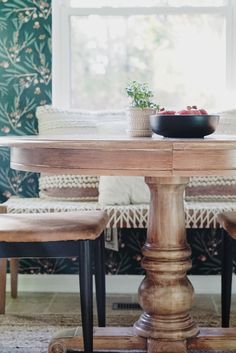 a wooden table with two chairs and a bowl of fruit sitting on top of it