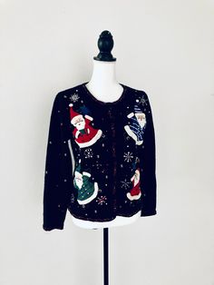 a black sweater with santa claus and snowflakes on it is sitting on a mannequin