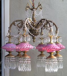 two chandeliers with pink and gold shades hanging from the ceiling