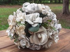 a bridal bouquet made from old book pages sits on a table in the park