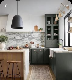 a kitchen with green cabinets and marble counter tops