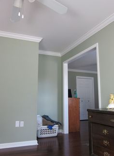 an empty room with a dresser and ceiling fan