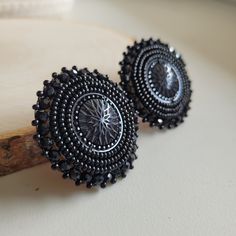 These earrings are made with seed beads and black centers encircled in black rhinestone. They are then branded with our logo, backed with moose hide and your choice of earring findings. The edging is done with black rondelle beads, creating and extra bit of sparkle as the earrings move about. Each pair are made with hypoallergenic materials for sensitive ears. You can now upgrade your earring to include a tassel attachment. This upgrade allows you to have a 3 in 1 pair of earrings. The tassel ea Round Beaded Earrings, Indigenous Earrings, Beaded Earrings Black, Black Beaded Earrings, Earring Inspo, Shoulder Duster Earrings, Beaded Jewlery, Earrings Black, Black Rhinestone