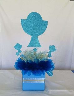 a blue vase with some flowers in it on top of a white cloth covered table