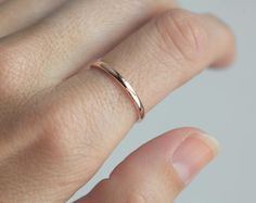 a close up of a person's hand with a gold ring on their finger