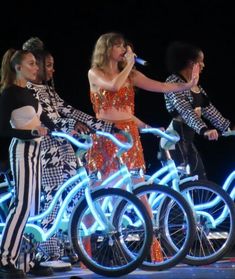 the group of women are performing on stage with their bike's in front of them