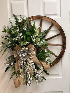 a wreath hanging on the front door of a house with greenery and ribbons tied around it