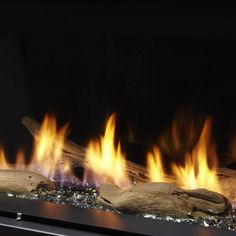 a fire burning in an open fireplace with rocks and logs on the bottom, as well as bright orange flames