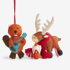 two stuffed animals hanging from strings on a white background, one is holding a guitar and the other is wearing a red scarf