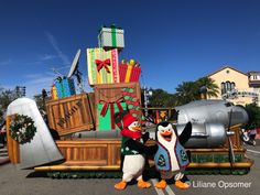 two penguins are standing in front of a float with presents on it's back