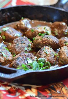 some meatballs are in a skillet on a red and white table cloth with green garnishes