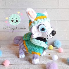 a crocheted dog wearing a sweater and hat with balls around it on the floor