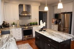 a large kitchen with marble counter tops and stainless steel appliances, along with white cabinets